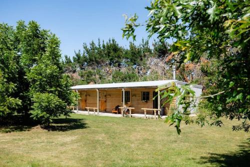 una cabaña de madera en un campo con árboles en Self contained & self serviced Farmstay in Waipara wine region, bath & fire en Waipara