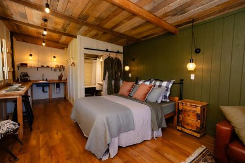 a bedroom with a large bed and a kitchen at Self contained romantic Farmstay in Waipara wine country with bath and fire in Waipara
