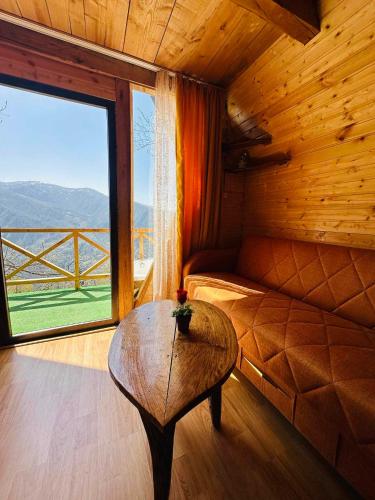 a room with a couch and a table with a large window at cottage panorama merisi in Inasharidzeebi