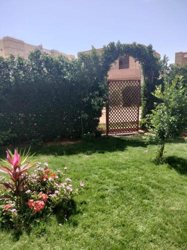 a garden with a gate and flowers in the grass at فيلا مريم in Cairo
