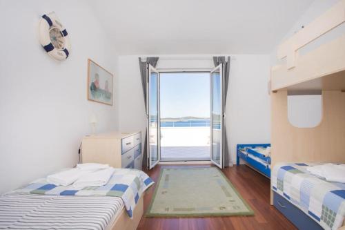 a bedroom with two beds and a sliding glass door at Amazing Mediterranean view Villa Oliva Zaboric in Zaboric