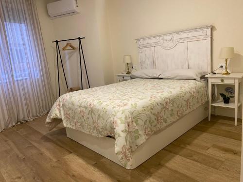 a bedroom with a white bed with a floral bedspread at Loft Nature en Bernabé Soriano in Jaén