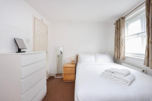 a bedroom with a white bed with towels on it at Vibrant Clapham Double bedroom in London
