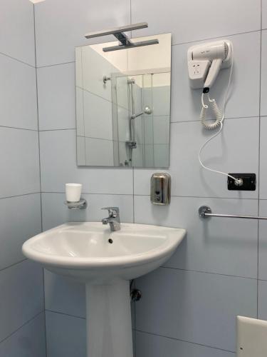 Baño blanco con lavabo y espejo en B&B Albergo Centrale Gioiosa Ionica, en Gioiosa Ionica
