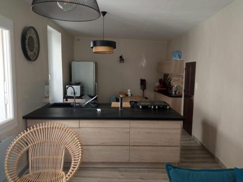 une cuisine avec un comptoir noir et une chaise dans l'établissement Maison de village Sarrians, à Sarrians