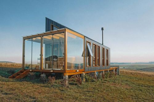 Soular Lodge e Fazenda في ساو فرانسيسكو دي باولا: عبارة عن منزل زجاجي يقع فوق حقل