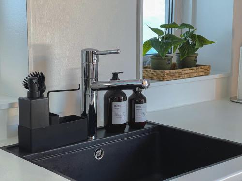 a black bathroom sink with two bottles on it at The Black House Tuapannguit 48 in Nuuk