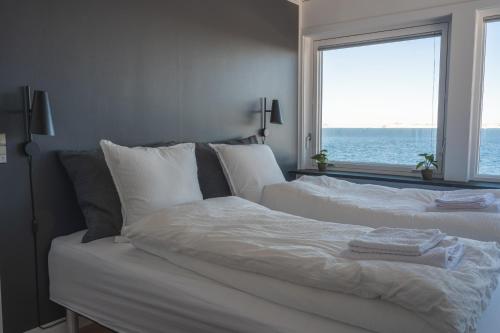 a bedroom with a white bed with a view of the ocean at The Black House Tuapannguit 48 in Nuuk