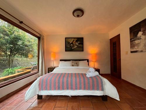 a bedroom with a large bed and a large window at ApartaHotel La Leyenda in Villa de Leyva