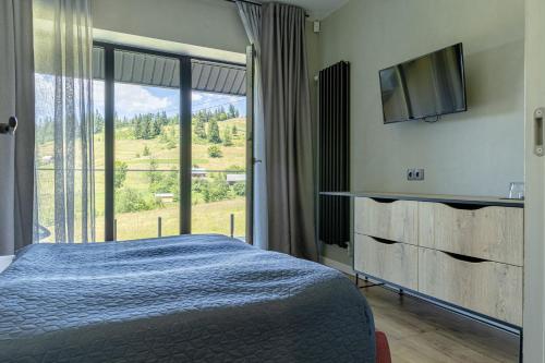 um quarto com uma cama e uma grande janela em Котеджі Лісові Форелі em Yablunytsya