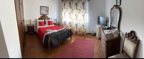 a bedroom with a red bed and a television at Propriedade dos Seixos in Moledo
