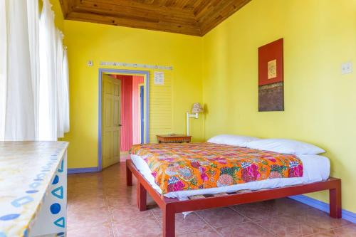 a bedroom with a bed and a yellow wall at Taino Cove in Treasure Beach
