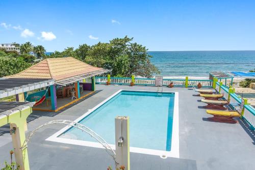 a swimming pool with lounge chairs and the ocean at Taino Cove in Treasure Beach