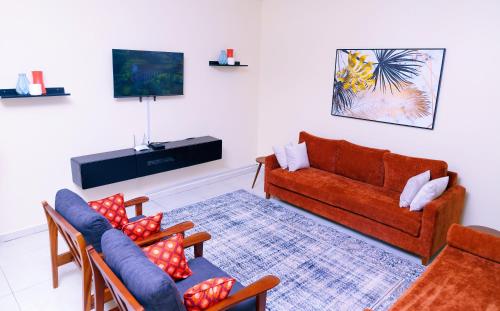 een woonkamer met een bank en stoelen en een tv bij Ahva II Residence in Jinja