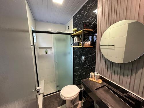 a bathroom with a toilet and a sink and a mirror at Aconchegante Quitinete Próximo ao Centro/Criciúma. in Criciúma