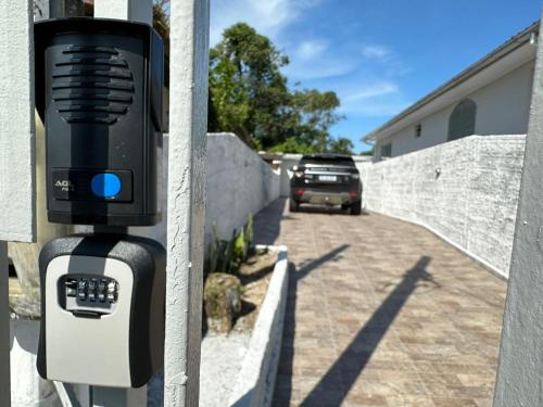 a parking meter attached to a wall with a car driving down a street at Aconchegante Quitinete Próximo ao Centro/Criciúma. in Criciúma