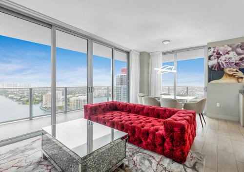 HYDE BEACH HOUSE #2408 THREE-BEDROOM, WATERFRONT, OCEAN AND INTERCOSTAL VIEW, ROOFTOP POOL, 5 MiN WALK TO BEACH في هوليوود: غرفة معيشة مع أريكة حمراء ونوافذ كبيرة