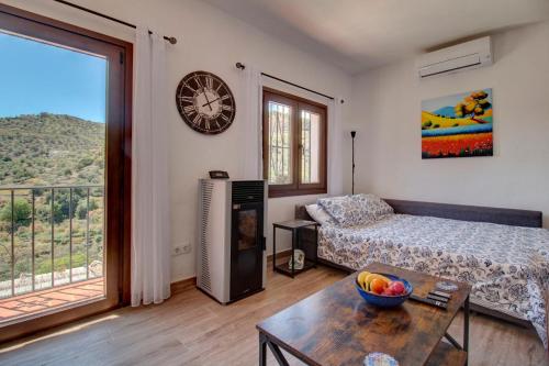 uma sala de estar com um sofá e um relógio na parede em Finca el Almendro Archez em Árchez
