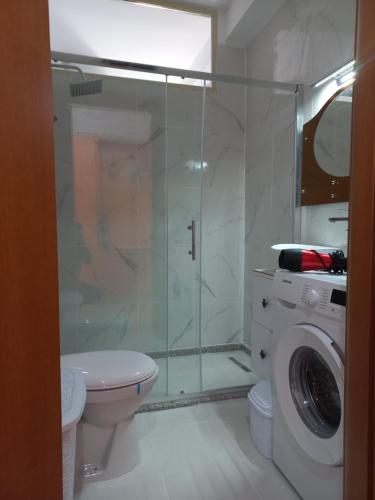 a bathroom with a shower and a washing machine at Lungomare Apartament Sea View in Vlorë