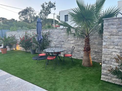 a patio with a table and chairs and a palm tree at ETOILE DU BERGER Saint Aygulf 3 Villas et 4 appartements jardin individuel et piscine chauffée - la mer et les plages 450 m in Saint-Aygulf