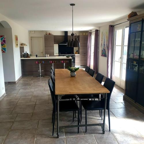une table de salle à manger avec des chaises et une cuisine dans l'établissement Magnifique villa au cœur des Cévennes, à Saint-Privat-de-Vallongue