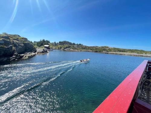 a boat traveling down a river with a red bridge at Seaside apartment - A9 in Nautnes