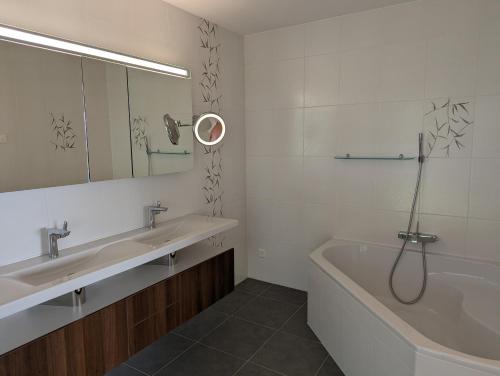 ein Badezimmer mit zwei Waschbecken, einer Badewanne und einem Spiegel in der Unterkunft 4,5 room apartment with lake view in Zug
