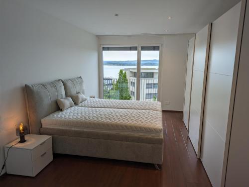ein Schlafzimmer mit einem Bett und einem großen Fenster in der Unterkunft 4,5 room apartment with lake view in Zug