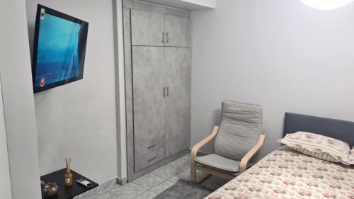 - une chambre avec un lit, une chaise et une télévision dans l'établissement JOHNNY APARTMENt, à Kavala