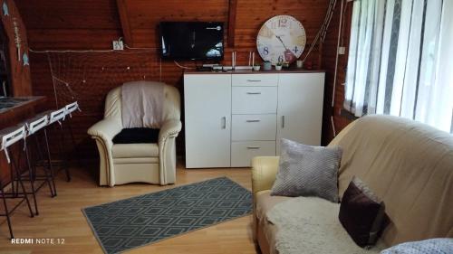 ein Wohnzimmer mit einem Sofa, einem Stuhl und einem TV in der Unterkunft Balatonmáriafürdő Szabó apartman in Balatonmáriafürdő