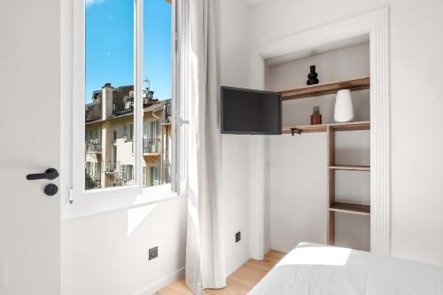 a white bedroom with a window and a door at RIVIERA COZY - Place Massena in Nice