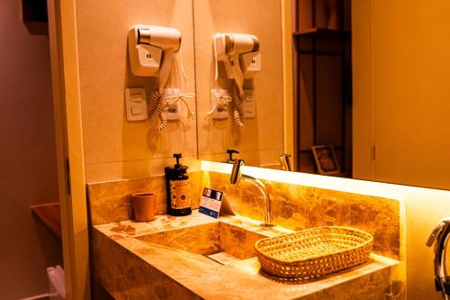 un lavandino del bagno con un cestino di vimini e uno specchio di Pousada Sollari a Mundaú