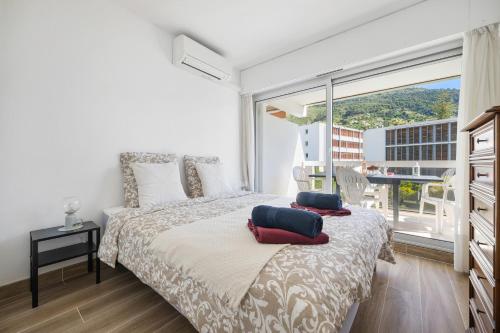 a bedroom with a bed and a large window at ROCAMARE Piscine toit terrasse - Parking privée - Terrasse in Menton