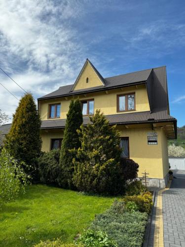 une maison jaune avec un toit noir dans l'établissement Pokoje i Apartamenty Regionalny Styl ul Bachledy 41 Zakopane, à Zakopane