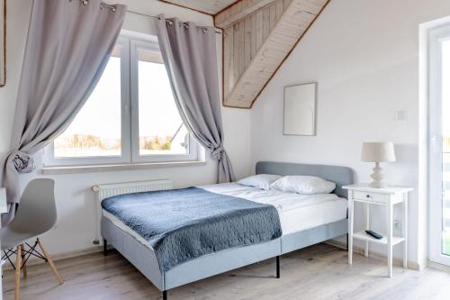a white bedroom with a bed and a window at Cichy Domek - Podgrzewany Basen, Parking, Aneks Kuchenny in Karwia