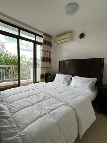 a large white bed in a bedroom with a balcony at Secluded-Loft-2 BEDROOM-2-Bath in Dar es Salaam