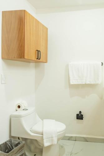 a white bathroom with a toilet and a wooden cabinet at Casa Nawalli Puerto Vallarta Boutique Hotel - Adults Only in Puerto Vallarta
