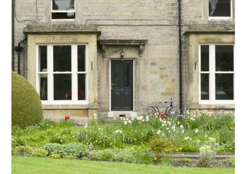 a house with a black door and some flowers at The Beeches - Chatsworth Apartment No 1 - Sleeps 4 in Baslow