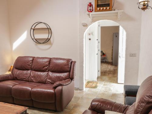 a living room with a brown leather couch and an entry way at Teach Phaidí Mhóir in Donegal