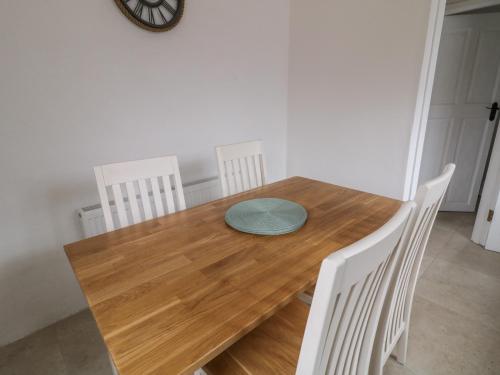 a wooden table with four chairs and a clock on the wall at Teach Phaidí Mhóir in Donegal