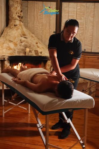 a man laying on a bed while a man is getting a massage at Entrebosques in Santa Elena
