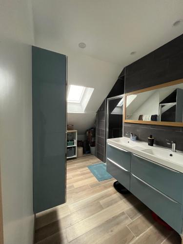 une salle de bain avec un lavabo et un miroir dans l'établissement En bord de mer, vue et accès direct à la plage, à Batz-sur-Mer