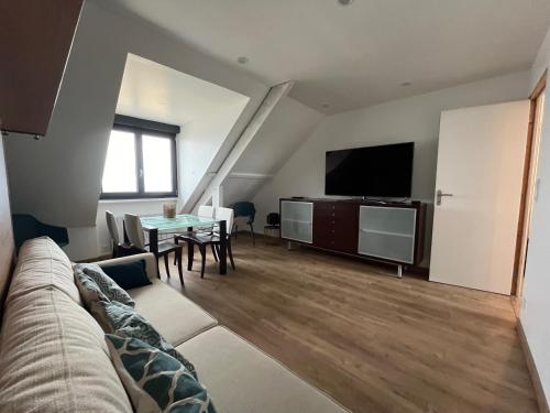 a living room with a couch and a tv and a table at En bord de mer, vue et accès direct à la plage in Batz-sur-Mer