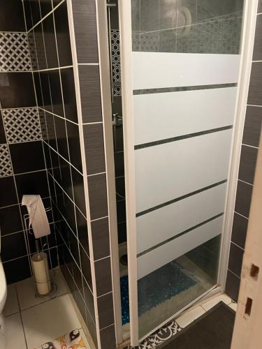 La salle de bains est pourvue d'une porte de douche et de carrelage noir et blanc. dans l'établissement T2 devise appartement center ville, à Bordeaux