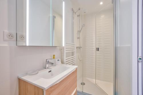 ein weißes Bad mit einem Waschbecken und einer Dusche in der Unterkunft Appartement calme vue Château in Versailles