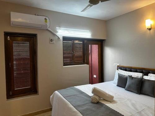 Schlafzimmer mit einem Bett, einem Ventilator und Fenstern in der Unterkunft Pixels Luxury Modern Apartment 5 Min to Palolem Beach in Canacona