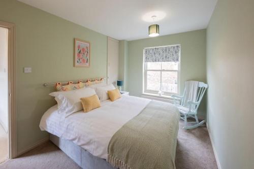 una camera da letto con un grande letto bianco e una sedia di Sheriffs Tower Cottage - East a Bishop Auckland