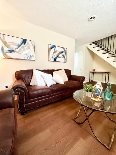 a living room with a leather couch and a glass table at Charming 3BR 1.5BA Cozy Haven in Rome