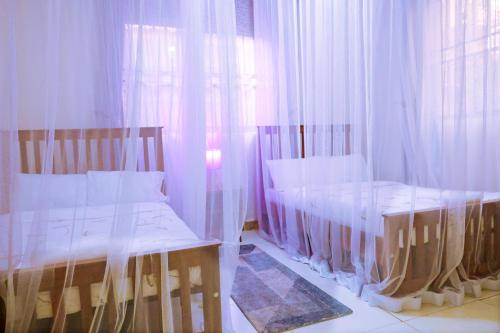 een slaapkamer met 2 bedden en een raam met gordijnen bij Ahva II Residence in Jinja