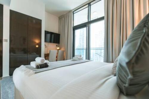 a bedroom with a white bed with a large window at Gorgeous Apt Studio with balcony in Business Bay in Dubai